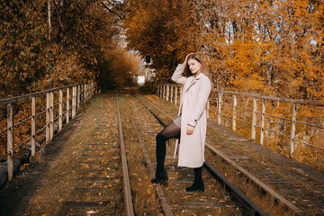 beautiful long-haired woman walks through the autumn streets. Railway, autumn, woman in a coat.