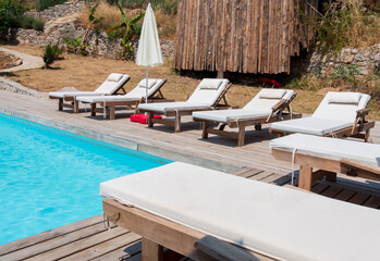 Sunbeds stand near the swimming pool.