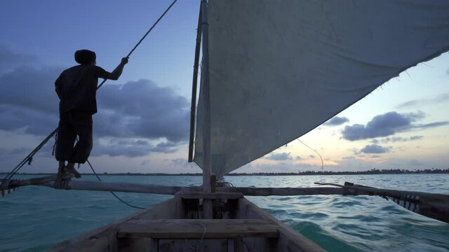 Outrigger sailing dhow travelling off the coast of Zanzibar. Tanzania. Africa.