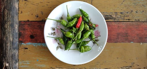 Bird's eye chilies on a white plate. On an aestethic wooden table background. Flat lay photos