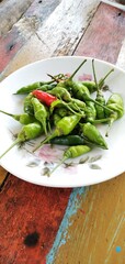 Bird's eye chilies on a white plate. On an aestethic wooden table background. Flat lay photos