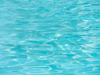 Shiny bright blue water surface in the swimming pool with waves.