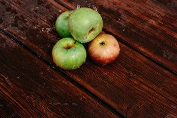Fresh autumn Apple harvest on the kitchen countertop. Four fresh apples lie on a wooden table. A textured mahogany wood background and fruit lie on it.