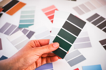 Woman hand choosing green and gray sample palettes.