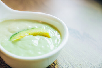 Fresh avocado smoothie with slices on wooden background
