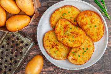 Sandwiches with fried potatoes and green onions. Delicious appetizer in a rustic style. Bread, salt, pepper and raw potato on the table. Selective focus