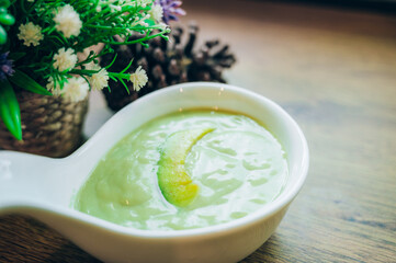 Fresh avocado smoothie with slices on wooden background