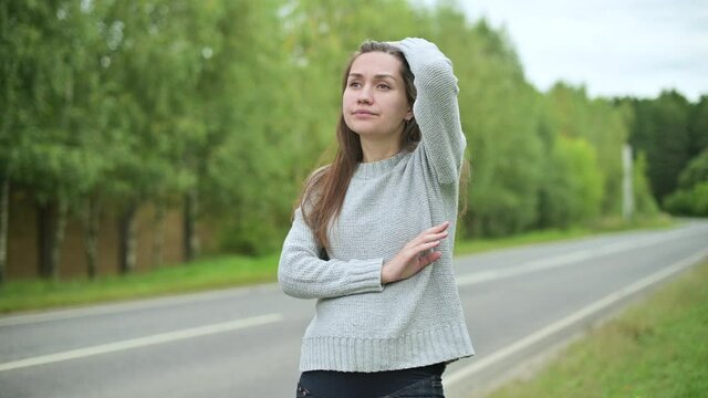 Close-up of a young woman waiting for a ride on a deserted country road
