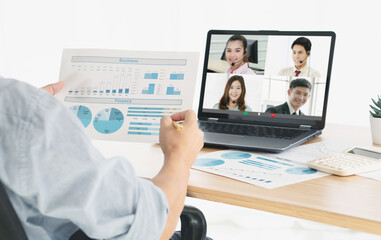 Group of businessmen and businesswomen smart working. View from side of man talking to her colleagues about business plan over a video conference.