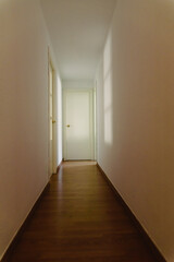 Scary light-walled hallway with a closed door illuminated by the dim shadow of a window, copy space.