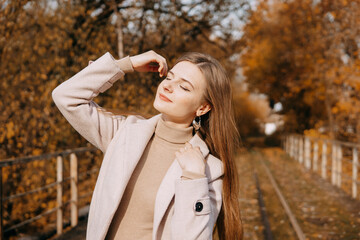 beautiful long-haired woman walks through the autumn streets. Railway, autumn, woman in a coat.