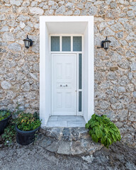 Fototapeta na wymiar white door and stone wall house by the sidewalk