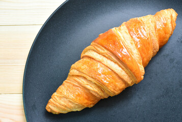 Croissants are placed in black plates that are placed on the wooden floor