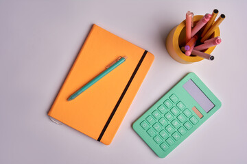 calculator with pen and yellow notepad on white background. office tools