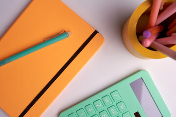 calculator with pen and yellow notepad on white background. office tools