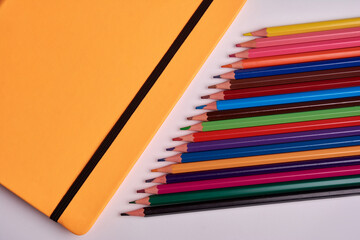 colored pencils and notepad on a white background