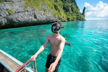 An active man on thai traditional longtail Boat is ready to snorkel and dive, Phi phi Islands, Thailand - obrazy, fototapety, plakaty