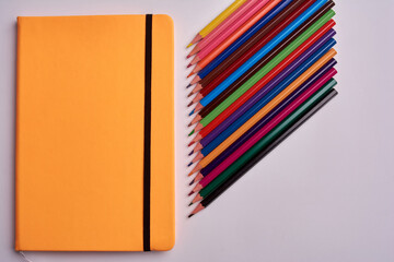 colored pencils and notepad on a white background