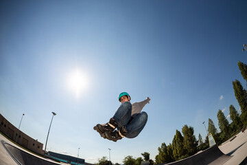 boy with inline skates, rollerblade, doing a jump in a skate park