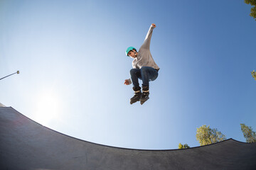 boy with inline skates, rollerblade, doing a jump in a skate park
