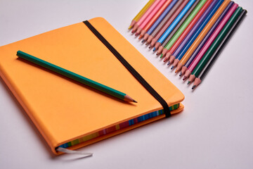 colored pencils and notepad on a white background