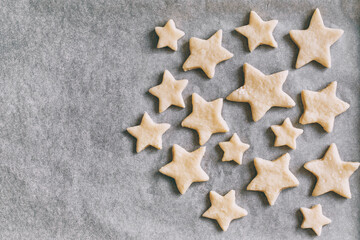 cookies in the form of stars on parchment paper lies in baking tray