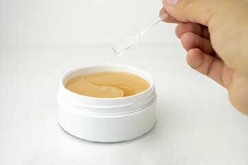golden under eyes patches in a white container, anti aging skin care, white wet background
