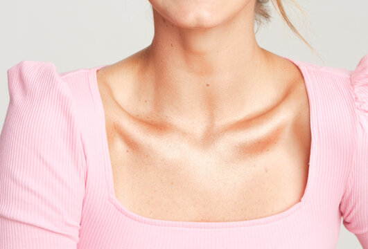 glossy flawless collarbone and neck of a blonde women wearing a pink shirt 