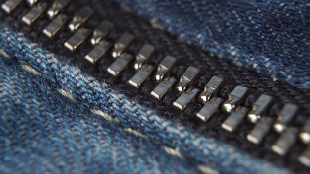 Closed metal zipper of jeans close-up. Blue denim fabric. Macro shot