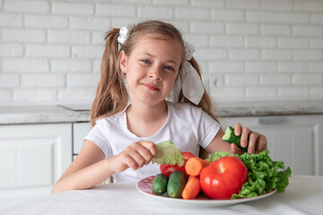little girl eats vegetables in the kitchen. healthy food. vegetarianism.