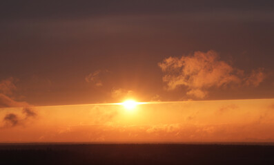 Bright orange sun at sunset with a clear horizon
