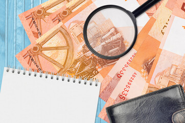 5 Belorussian rubles bills and magnifying glass with black purse and notepad. Concept of counterfeit money. Search for differences in details on money bills to detect fake