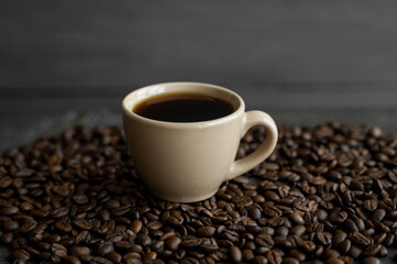 Cup of coffee with roasted coffee beans background. Mug of black coffee.