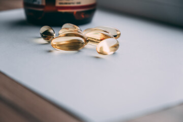 yellow transparent capsules omega 3 lie on a white background, on the background bottle. food additives concept