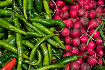 Red radish and hot chili peppers on market. Vegetables background.