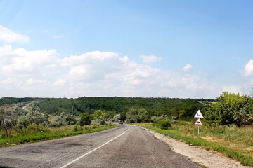 The road is in a rural location. Rural road. Asphalt road.