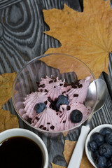 Zephyr in a glass. With biscuit and blueberries. Next to it is a cup of coffee and a saucer of blueberries. Among the maple leaves. On pine boards painted black and white.