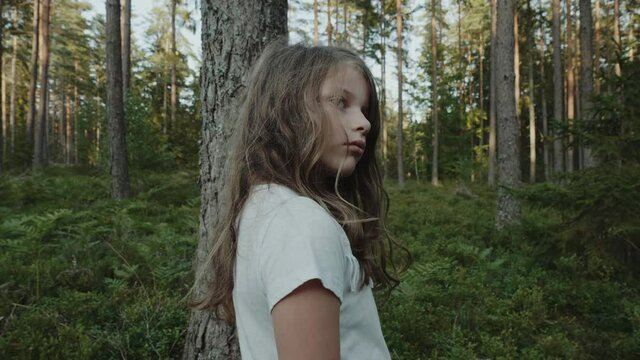 little cute girl standing in the middle of the forest alone