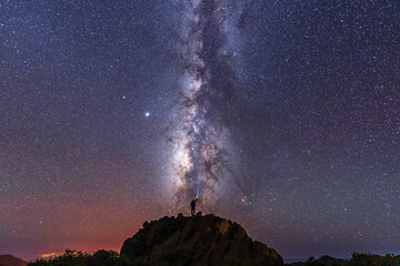 A young man with a flashlight below the beautiful milky way of the Caldera de Taburiente near the Roque de los Muchahos on the island of La Palma, Canary Islands. Spain, astrophotography