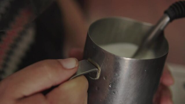 Professional barista heating milk, in a coffee machine