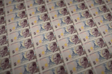 5 Turkish lira bills printed in illegal money production conveyor. Collage of many fake bills....