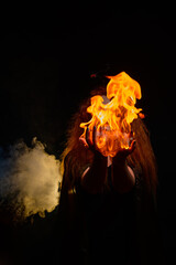 An evil red-haired witch holds fire in her hands.