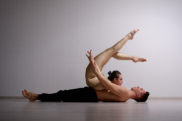 A duet of acrobats showing a pair trick. A woman in gymnastics overalls in a handstand over a...