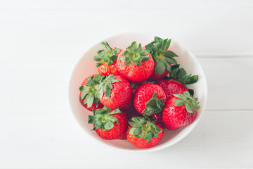 Close up, appetizing and colorful fresh strawberries in a white bowl, ready to eat. Selective focus, copy space
