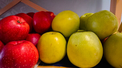 A Few Red And Green Apples Stand On A Wooden Shelf