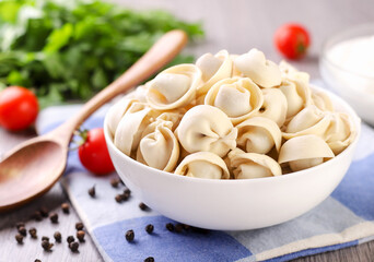 A plate of dumplings on the kitchen table with sour cream and vegetables
