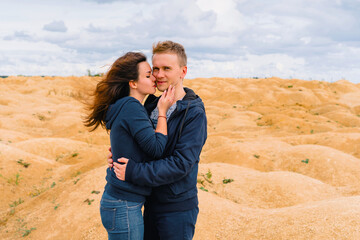 A couple of young lovers a man and a woman in the desert with sand dunes of bizarre shape