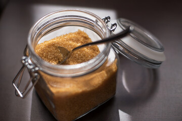Transparent glass jar with brown sugar cane on a black background