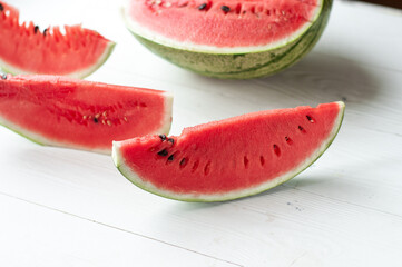 Fresh sliced watermelon and watermelon pieces on a wooden background.