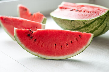Fresh sliced watermelon and watermelon pieces on a wooden background.